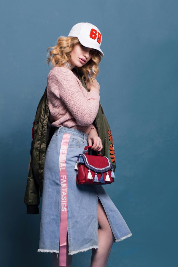 Trendy fashion model poses in a stylish studio setting, showcasing a chic outfit with accessories.