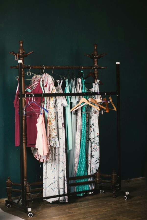 A stylish collection of dresses on a wooden clothes rack against a dark wall, creating a chic aesthetic.