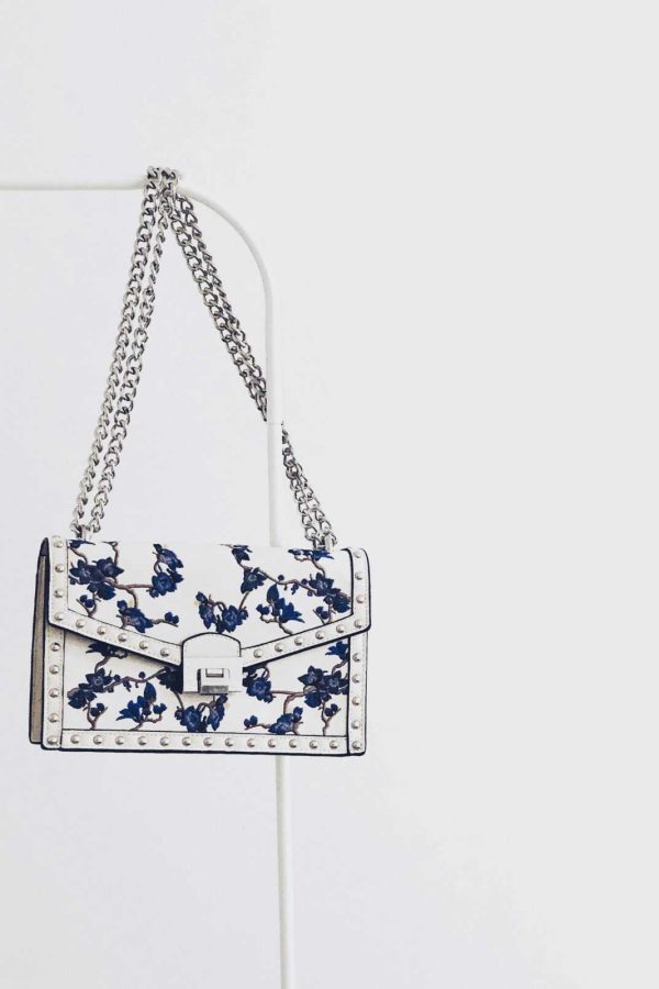 Elegant white handbag with blue floral design and silver chain, perfect for fashion enthusiasts.